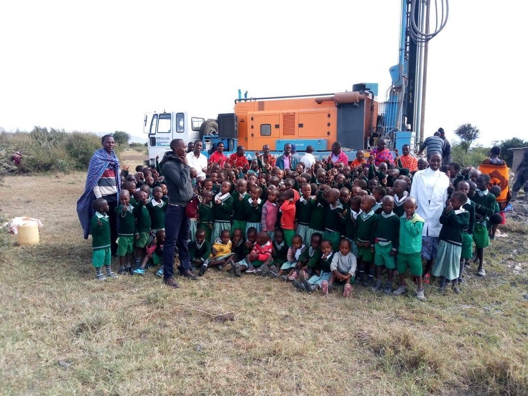 Drilling rig at school with students and teachers gathered around